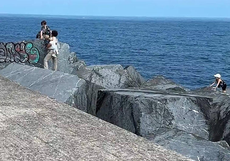 El padre, con sus hijos en las piedras del Paseo Nuevo de San Sebastián.