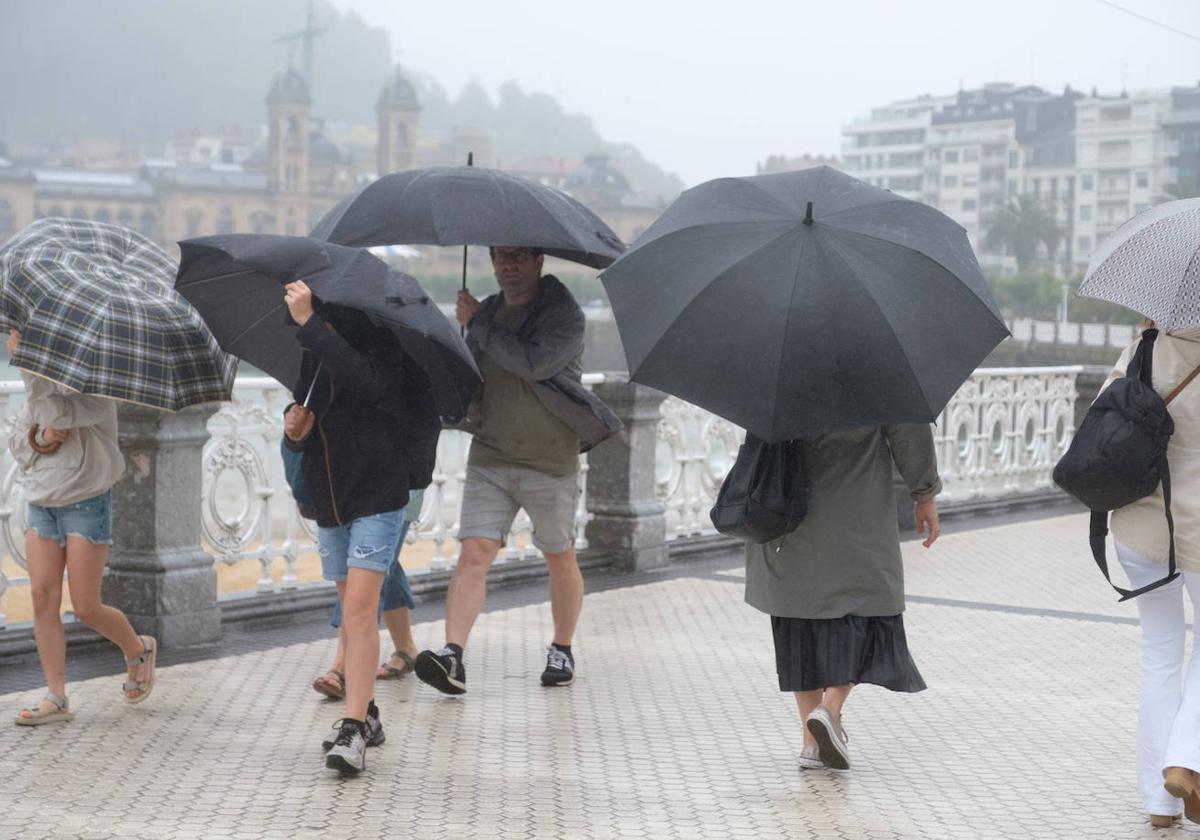 Los paraguas fueron indispensables para cubrirse de las lluvias y el viento en la jornada de ayer en Donostia.