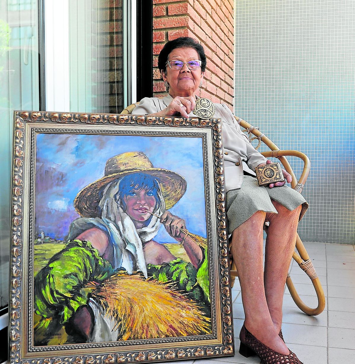 María Josefa Del Hierro posa con una pintura y dos trabajos de damasquinado en el balcón de su casa.