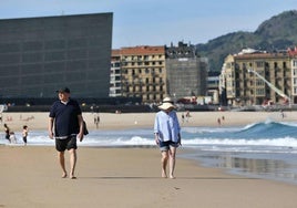 Dos personas pasean por la playa de La Zurriola.