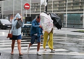 Unos turistas bajo la lluvia en Donostia.