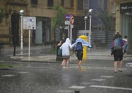 Varios jóvenes huyendo de la lluvia en Donostia.