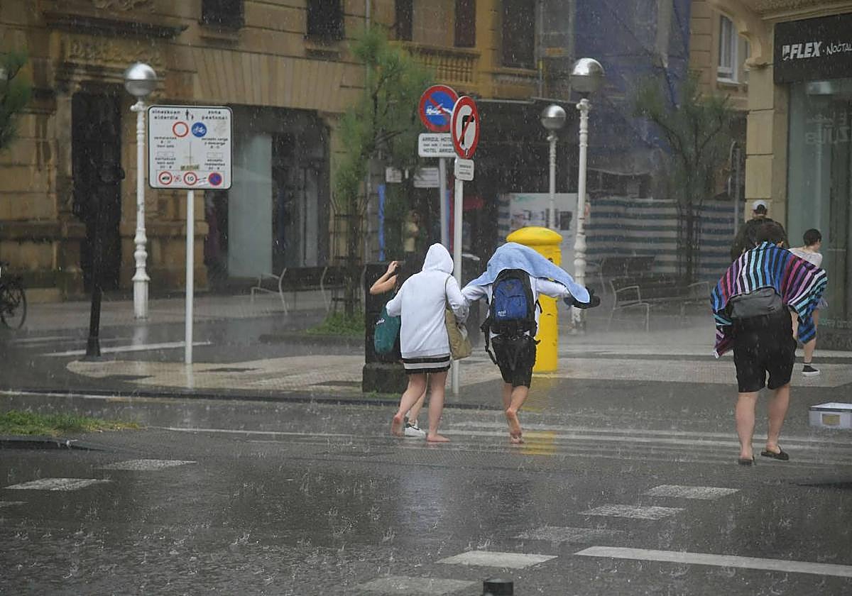 Varios jóvenes huyendo de la lluvia en Donostia.