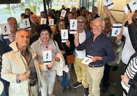 El escritor donostiarra Javier Postigo, a la derecha, muestra el libro 'Cartas al director', con escritos publicados en DV, rodeado de familia y amigos en la terraza del Café Victoria.