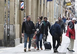 Unos turistas caminan con maletas por la Parte Vieja donostiarra.