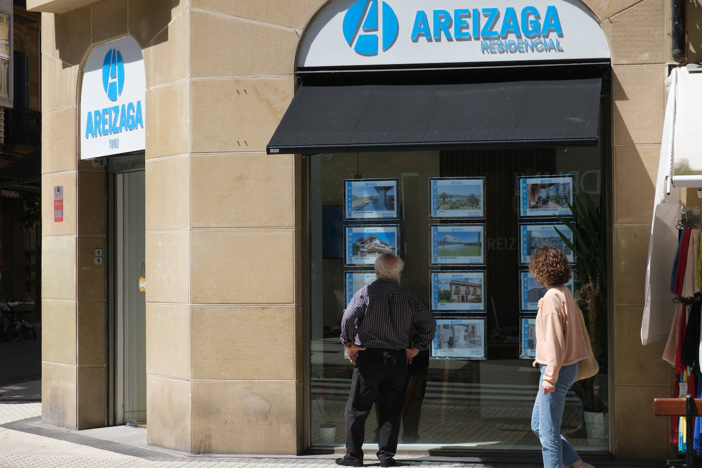 Viandantes observan anuncios de venta de casa en Donostia.
