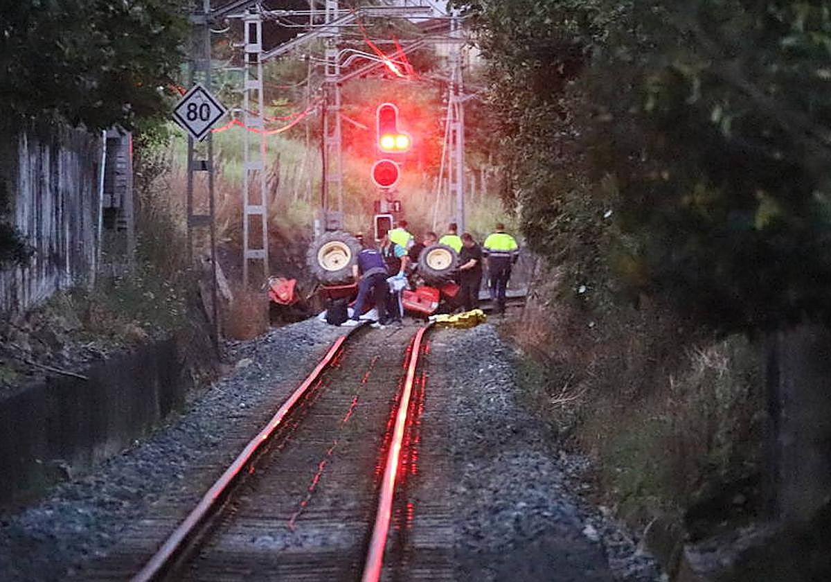 Efectivos de la Ertzaintza así como técnicos de ETS trabajan en la retirada del tractor accidentado de las vías del tren en Usurbil.