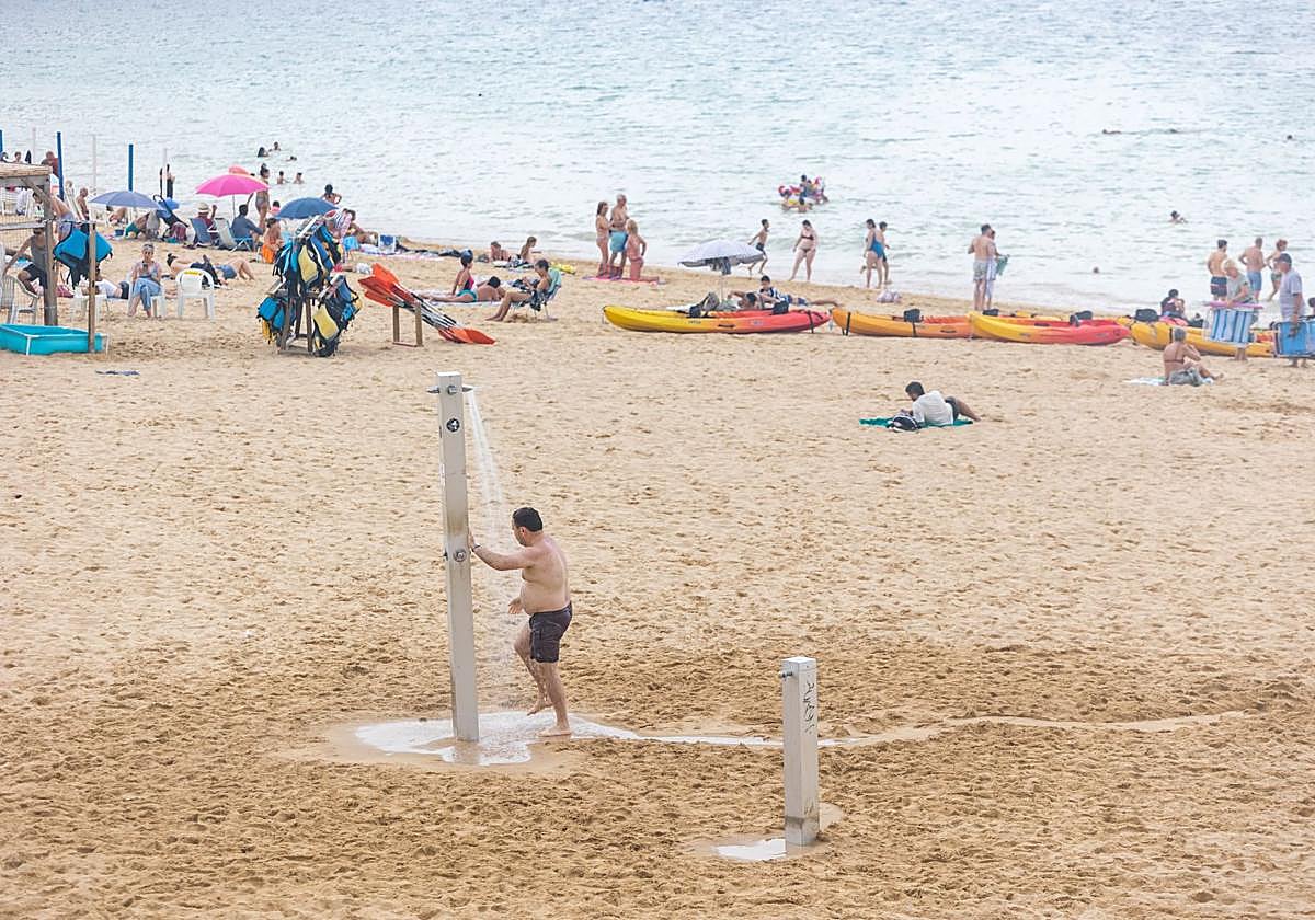 Un hombre se ducha en la playa para tratar de combatir el calor.