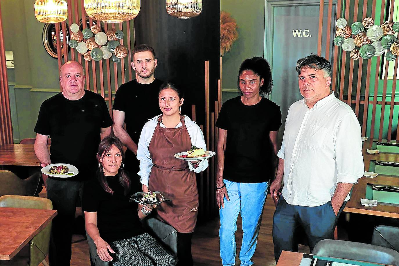 El equipo al completo de La Vinoteca, con algunos de los ricos platos que preparan.