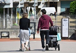 Una familia pasea con dos coches de bebé por Donostia.