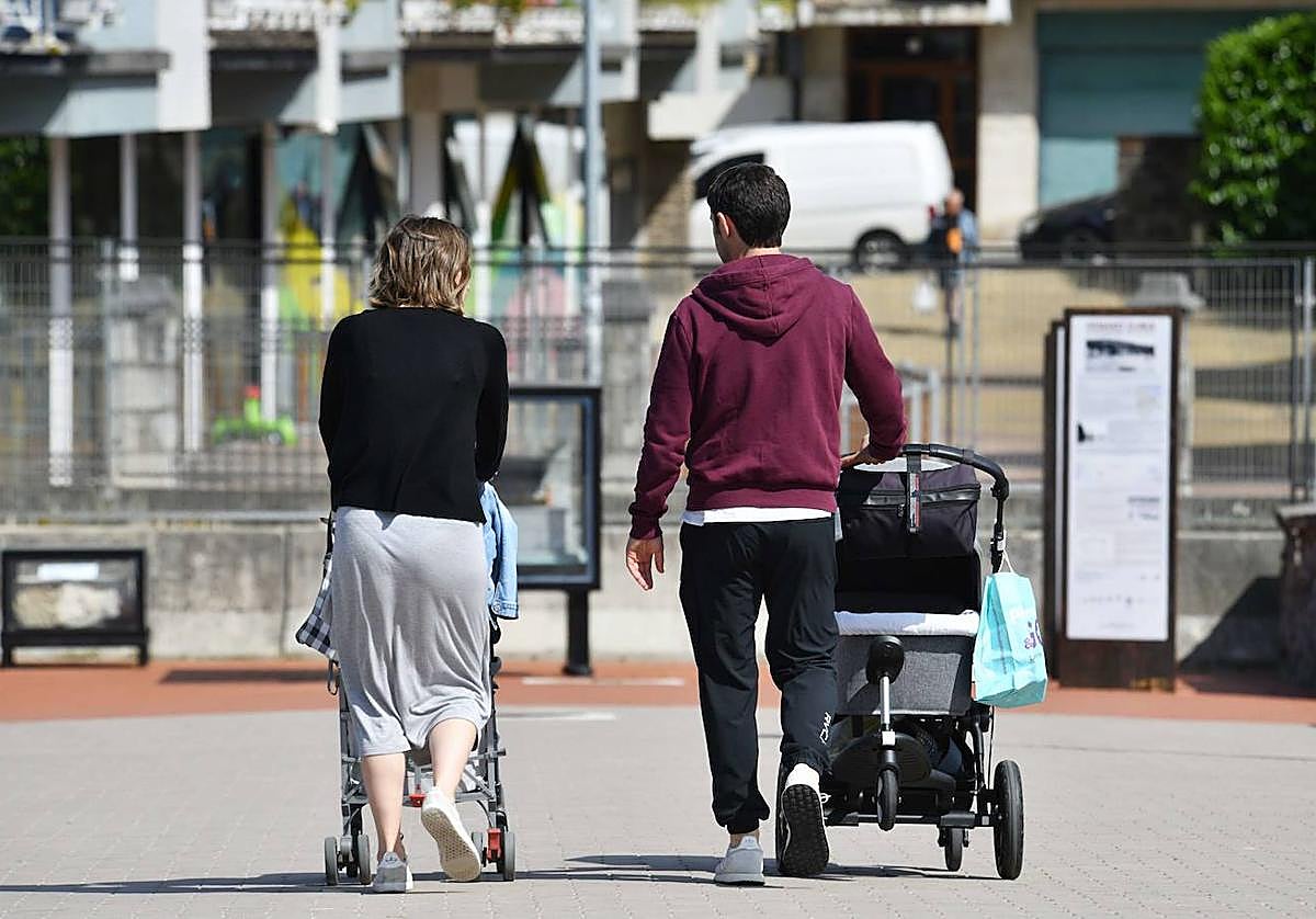 Una familia pasea con dos coches de bebé por Donostia.