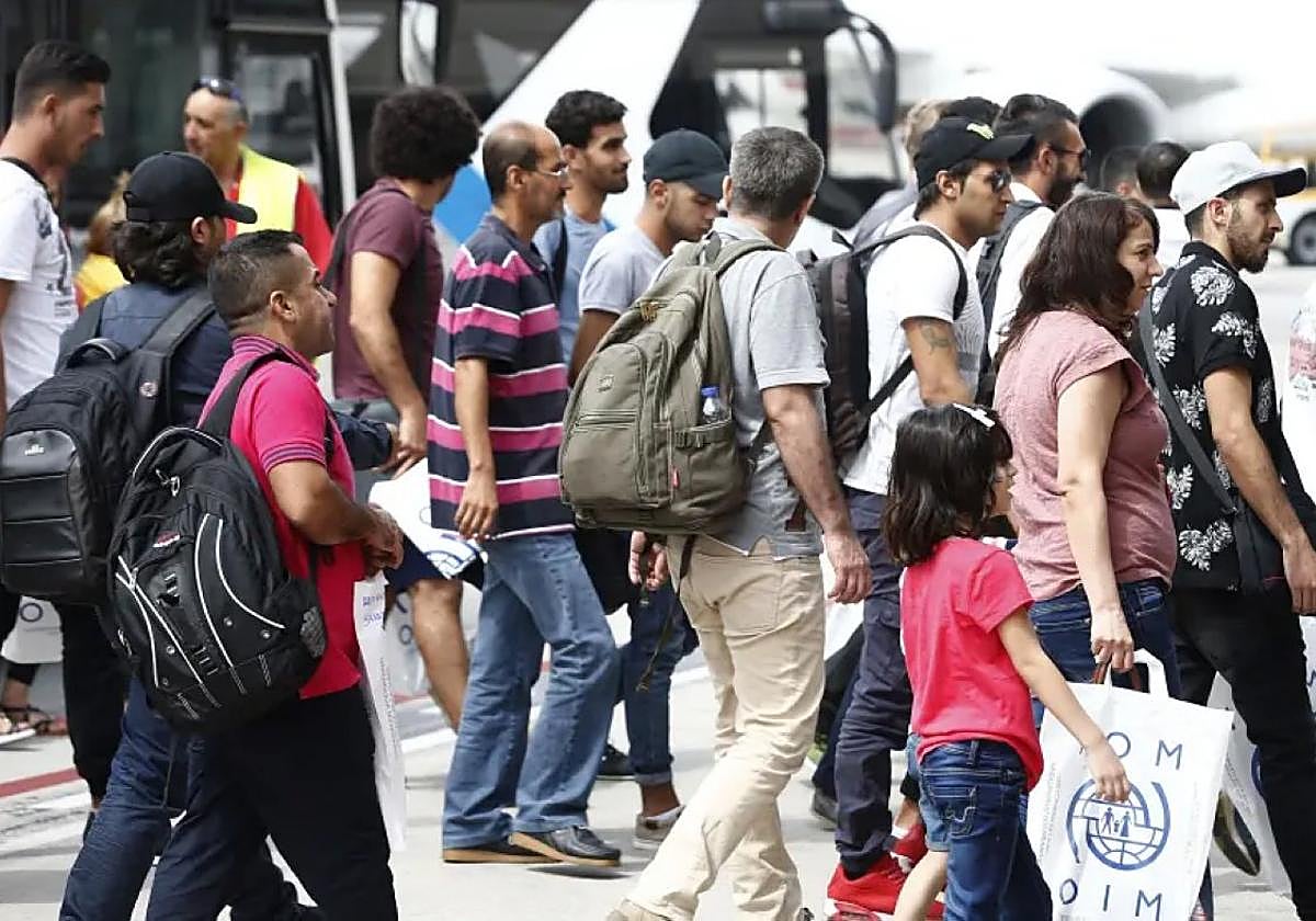 Varias personas de origen extranjero caminan por una calle.