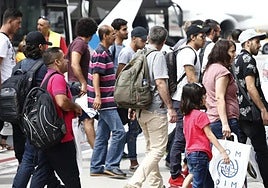 Varias personas de origen extranjero caminan por una calle.