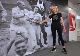 La maratoniana Kathrine Switzer posa en DV Gunea frente a su imagen corriendo el Maratón de Boston en 1967 con su dorsal número 261.