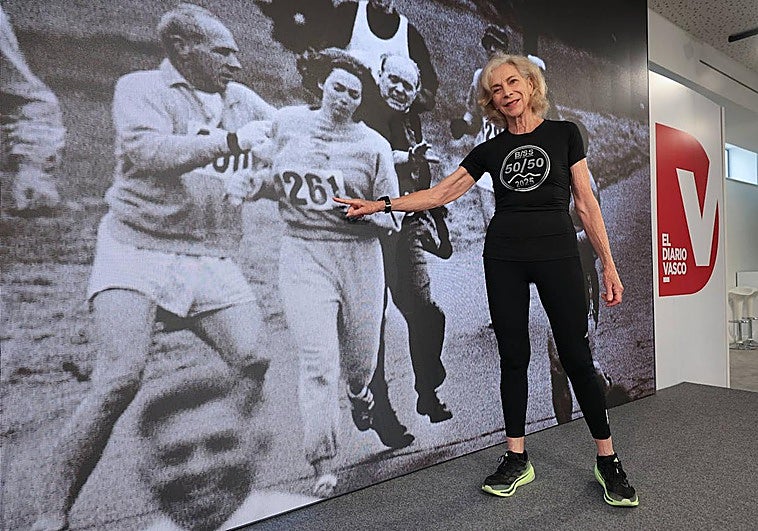 La maratoniana Kathrine Switzer posa en DV Gunea frente a su imagen corriendo el Maratón de Boston en 1967 con su dorsal número 261.