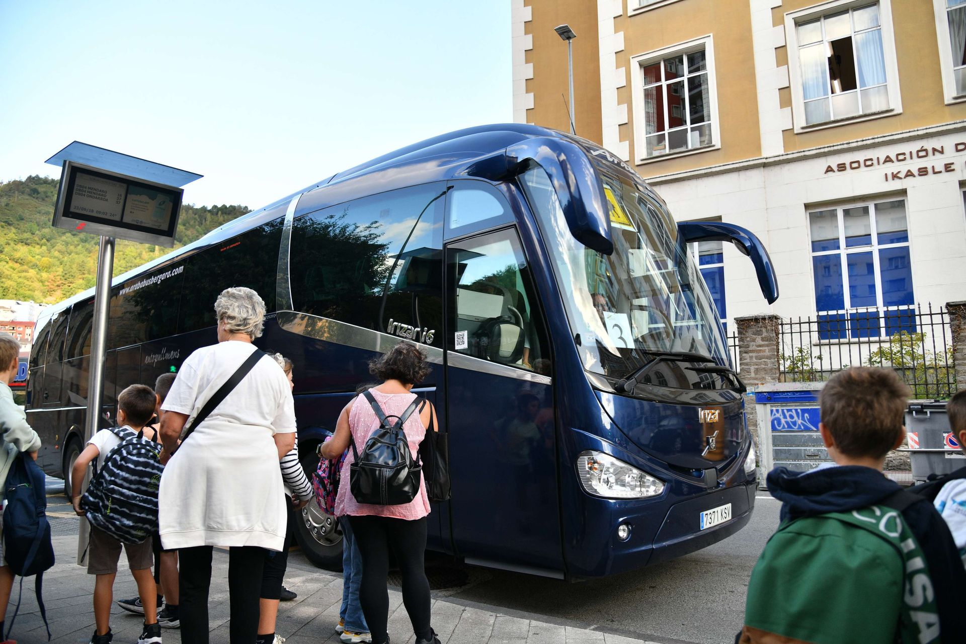 Varias familias recogen a sus hijos del autobús escolar.