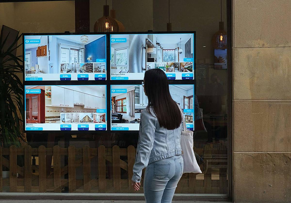 Una joven mira el escaparate de una inmobiliaria en Donostia.