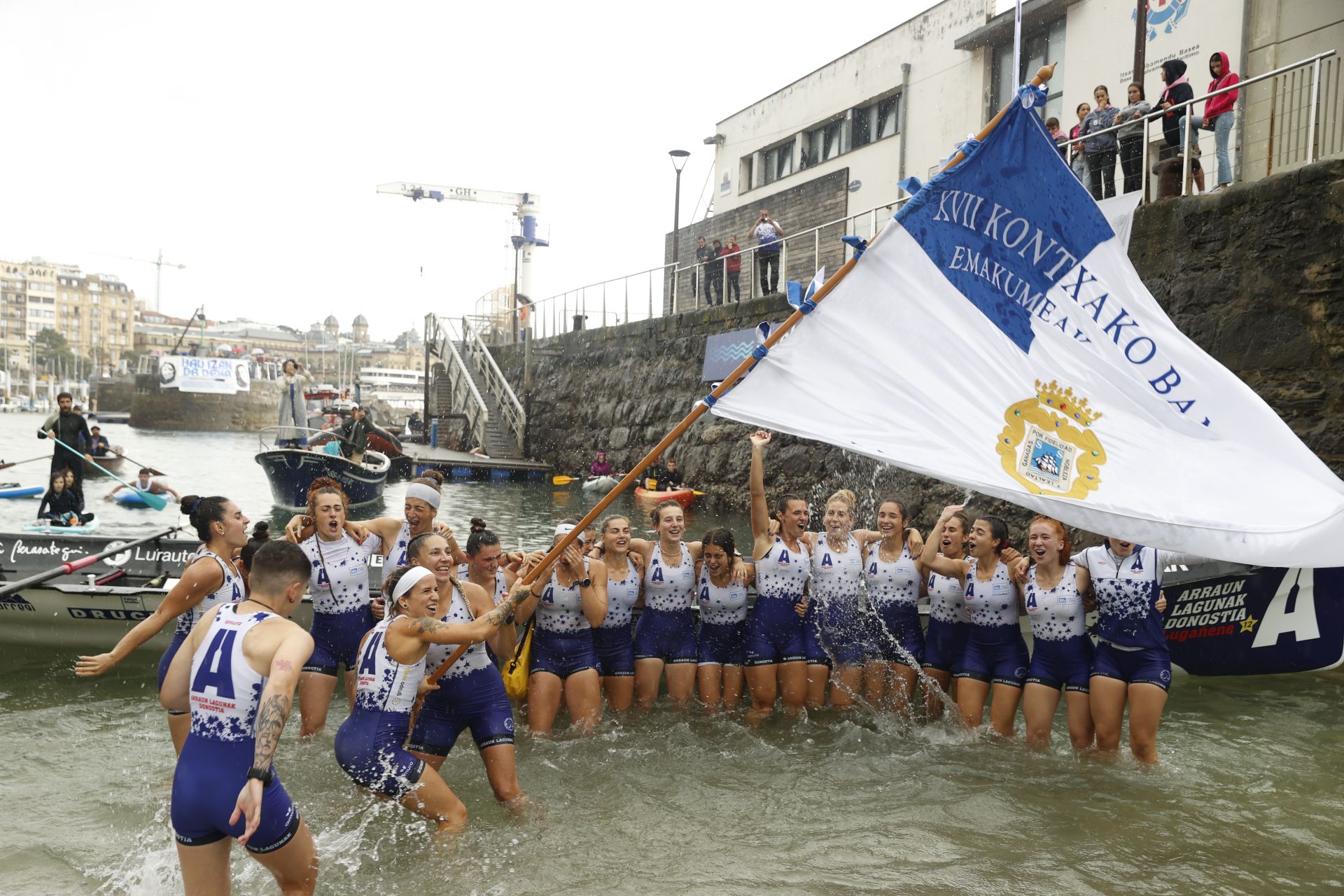 Las remeras de Arraun Lagunak ondean la Bandera de La Concha a su llegada a la rampa del muelle.