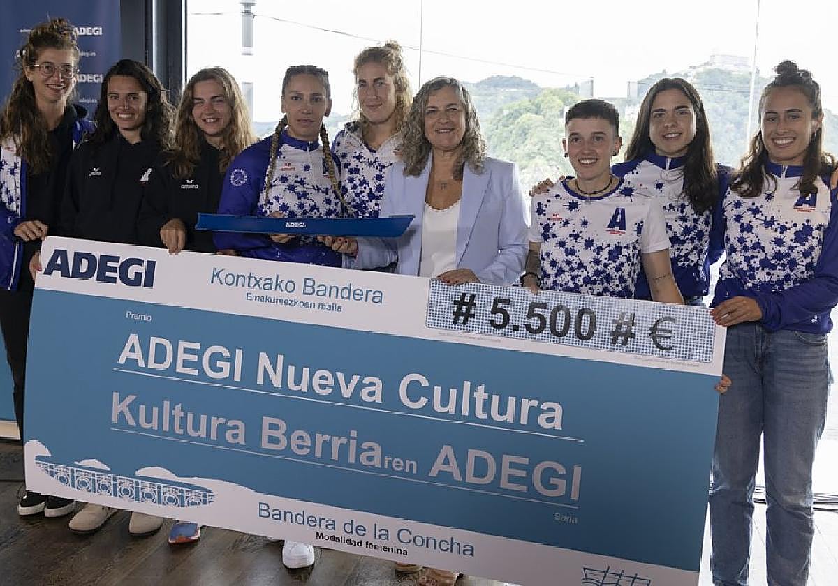 Las remeras de Arraun Lagunak posan junto a Isabel Busto con el talón del premio conseguido.