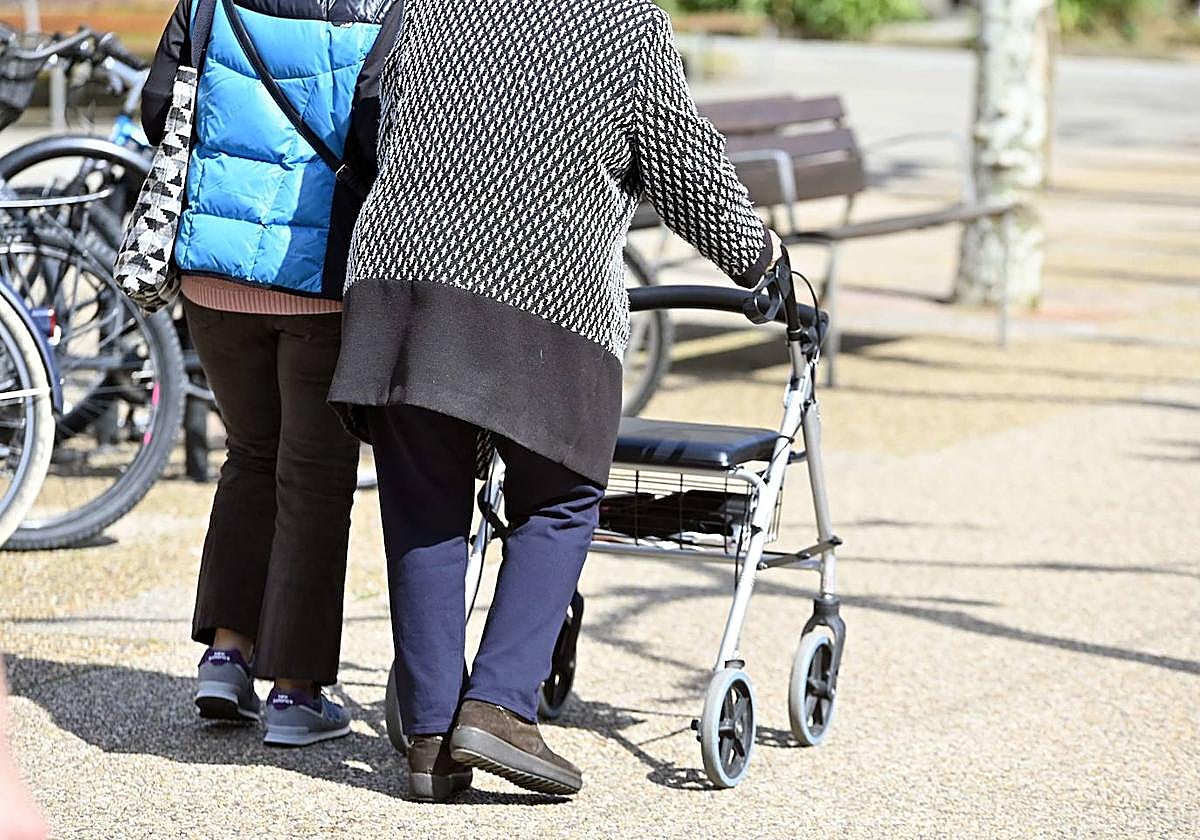 Un mujer mayor pasea por Tolosa junto a su cuidadora.