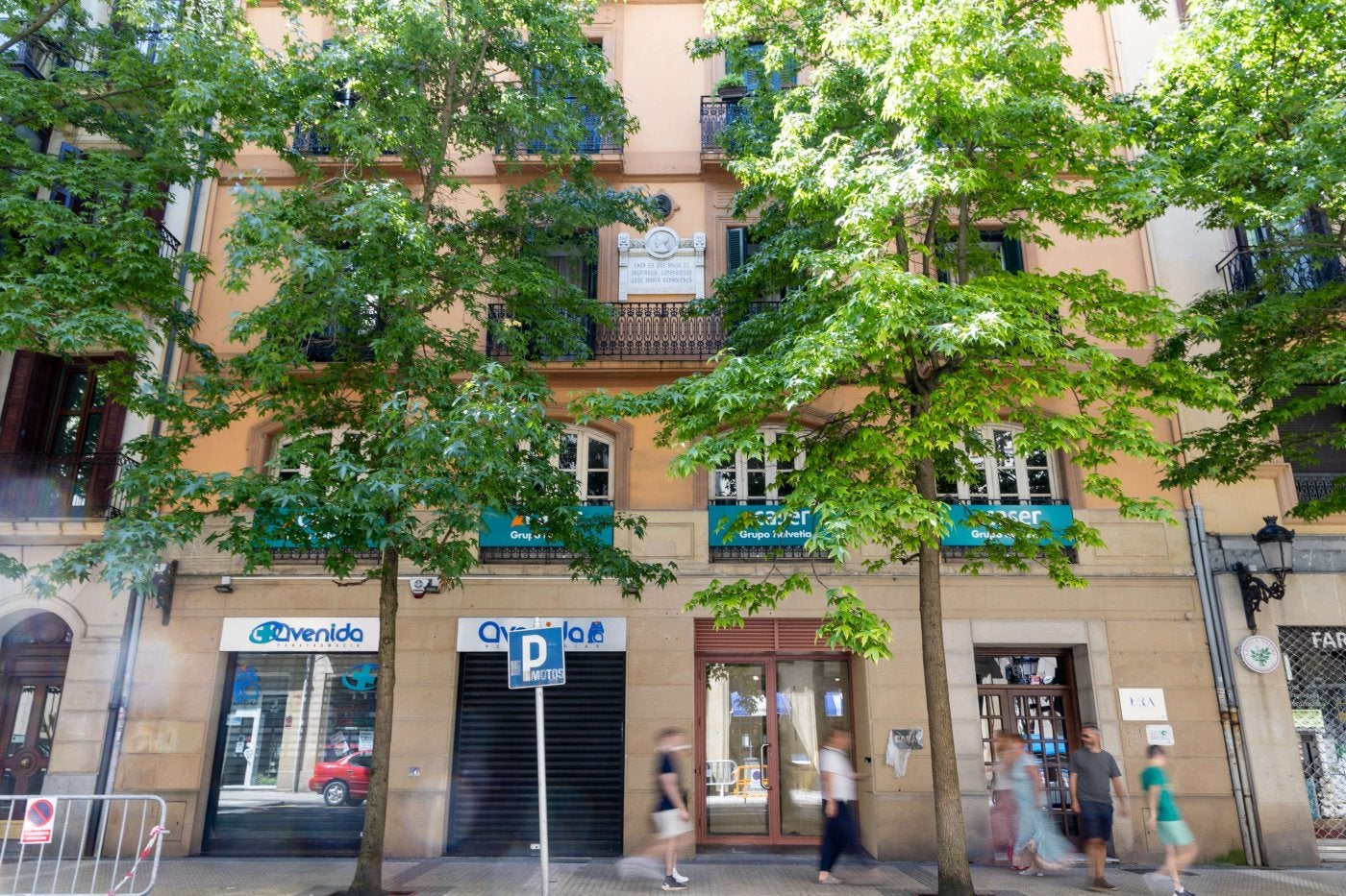 Varias personas pasean ante un edificio de viviendas en el centro de San Sebastián.
