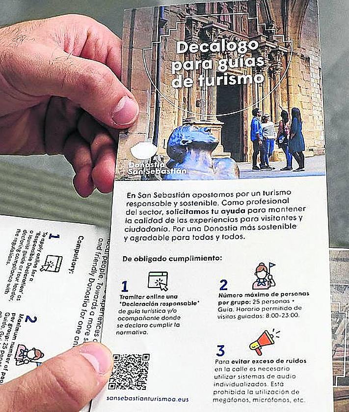 Imagen secundaria 2 - Las dos guías Ana y Cristina, el técnico de Donostia Turismoa junto al responsable de un grupo y una imagen del 'Decálogo del Buen Guía' que explica la normativa.