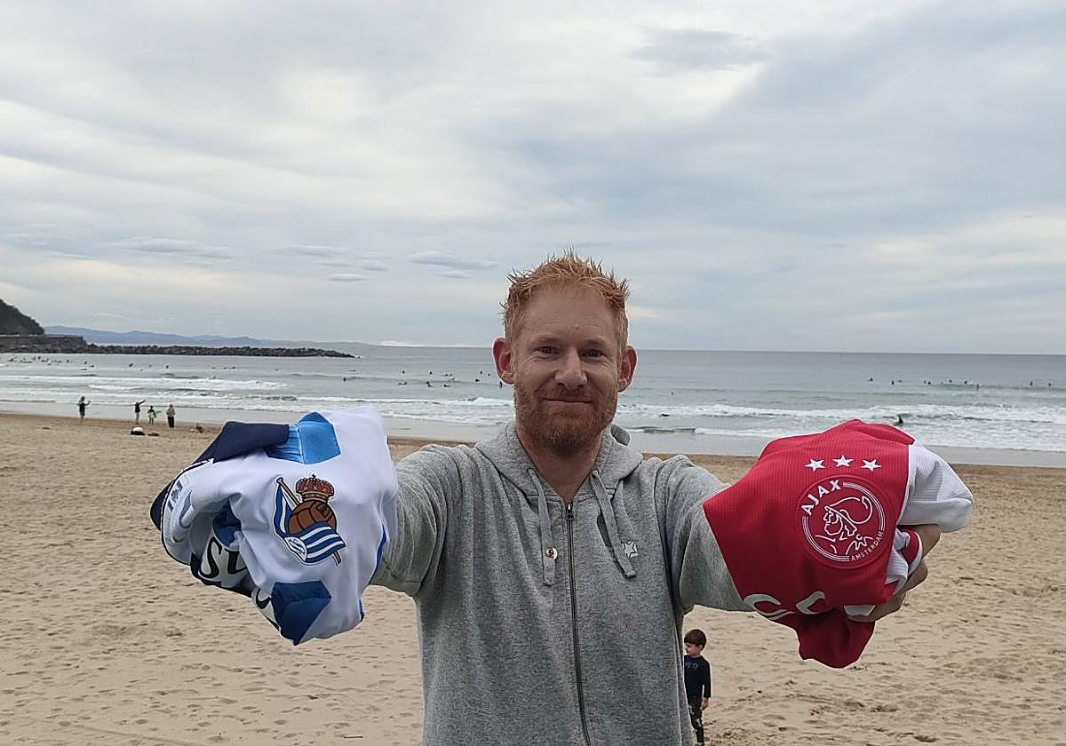 Ben Parham posa con las camisetas de la Real y el Ajax en La Zurriola.