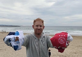 Ben Parham, un aficionado de la Real Sociedad y el Ajax, posa con las camisetas de los respectivos equipos en La Zurriola.