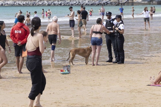 Dos agentes de la Guardia Municipal de San Sebastián charlan con la propietaria de un perro en la playa de La Concha.