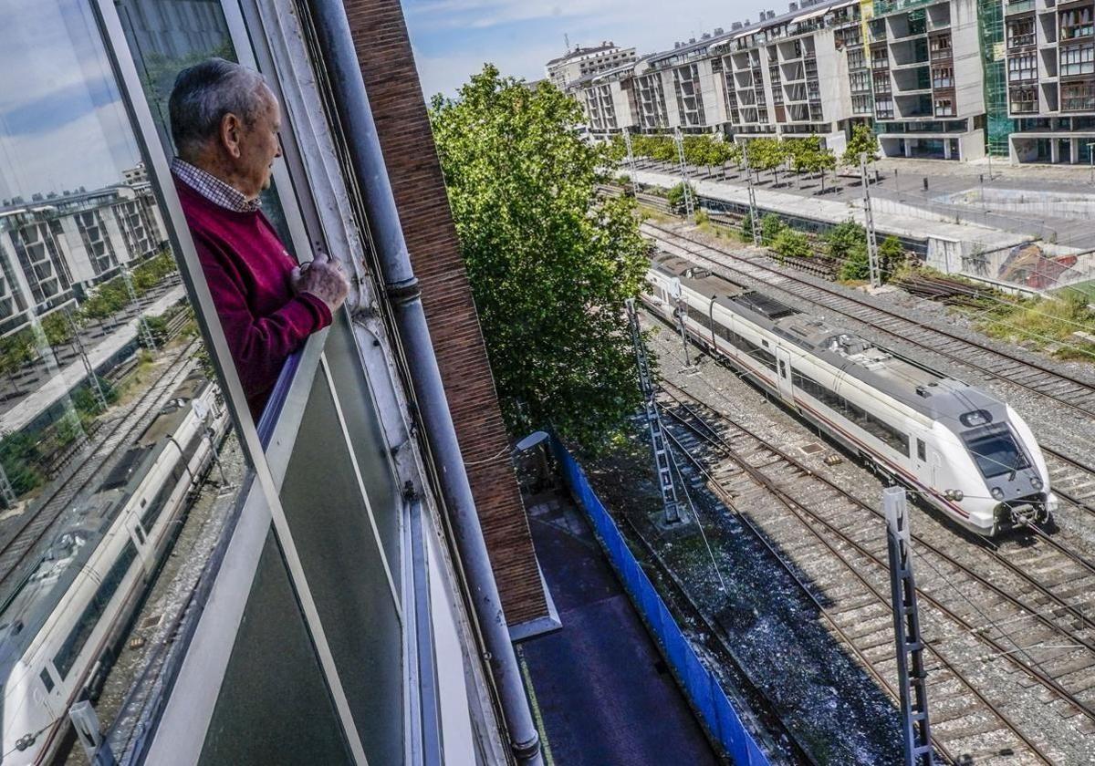 Un hombre observa desde su ventana un tren que abandona la estación de la calle Dato.