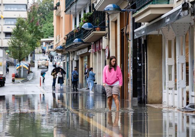 Una mujer intenta atravesar la calle Xenpelar de Errenteria, cubierta de agua