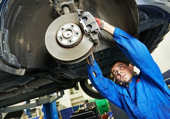 Imagen de archivo de un mecánico reparando un coche en un taller.