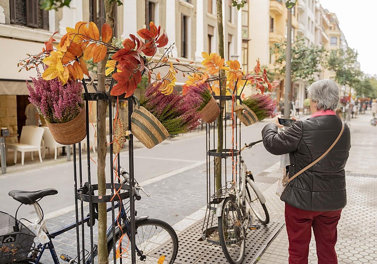 Una vecina de Gros saca una fotografía a la ornamentación otoñal colocada por la Sociedad de Fomento en la calle San Francisco de Gros este martes.