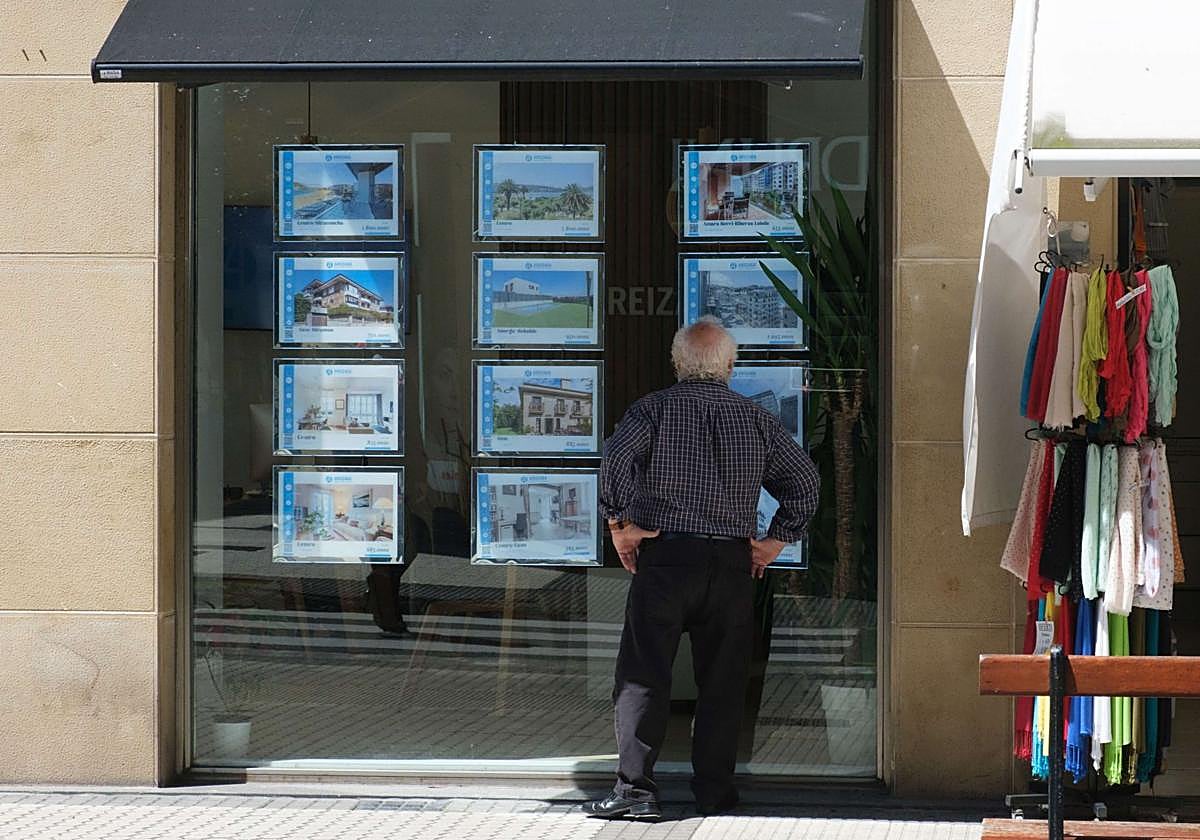Un hombre mira los anuncios de una inmobiliaria en el centro de San Sebastián.