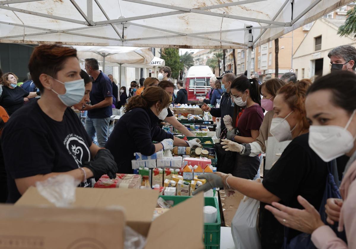 Vecinos de Paiporta se acercan a un punto de reparto de alimentos básicos,