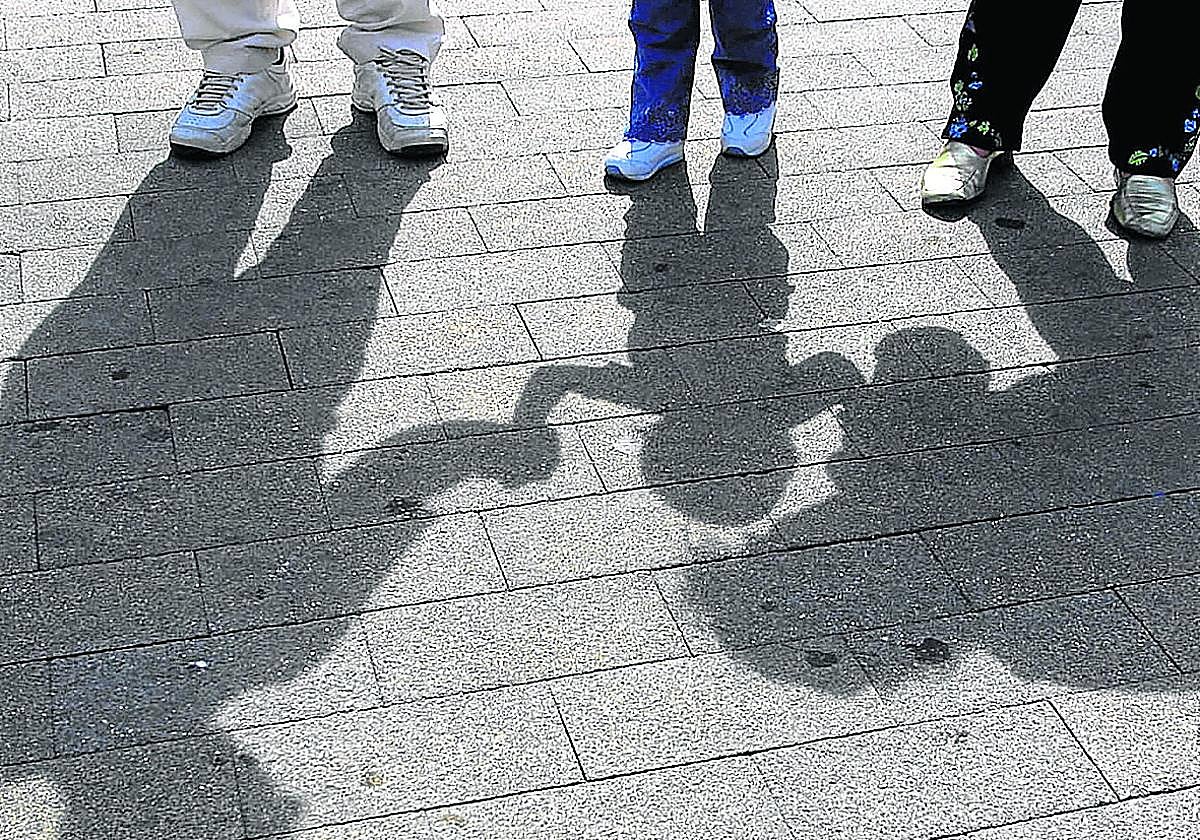 Un niño pasea de la mano de sus padres.