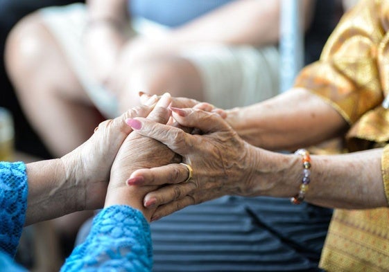 Imagen de archivo de dos personas mayores estrechándose la mano.