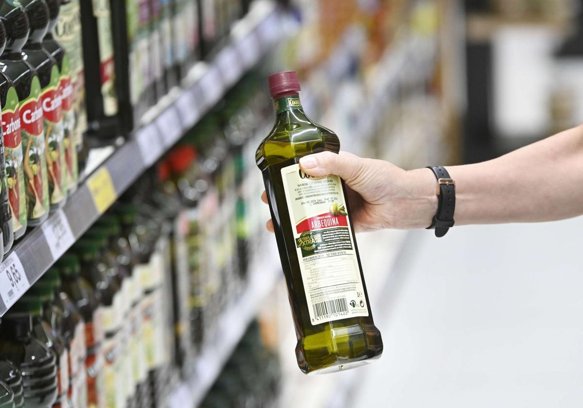 Un consumidor escoge una botella de aceite en un supermercado.