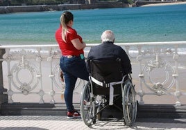 Una persona dependiente mira al mar en la barandilla de La Concha.