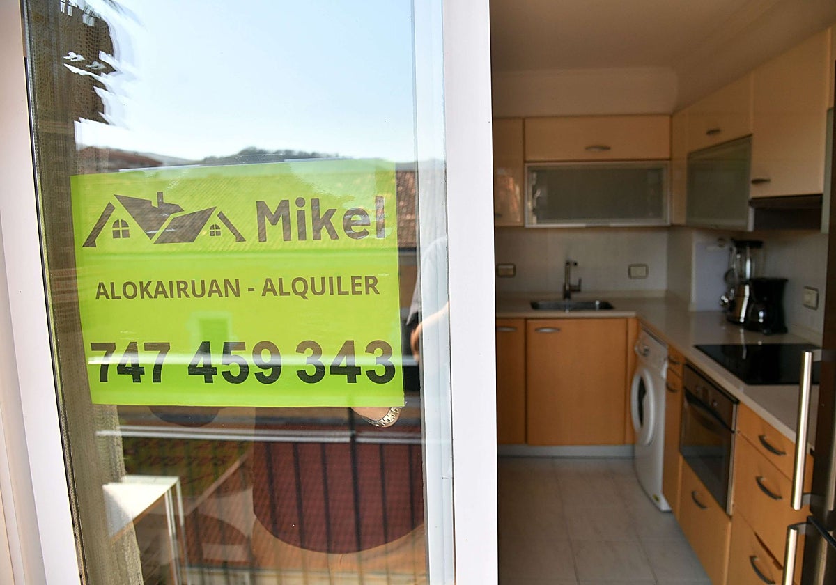 Un agente inmobiliario coloca un cartel de alquiler en una ventana.