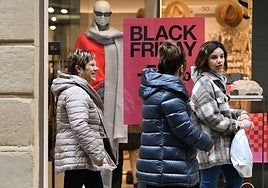 Varias personas pasan por delante del escaparate de una tienda San Sebastián, en una mañana de compras.