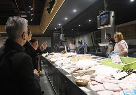 Clientes a la espera su turno en uno de los puestos de pescadería del mercado San Martín en Donostia, a donde muchos ya se acercan para hacer las compras navideñas.