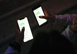 Dos alumnas, con los móviles.