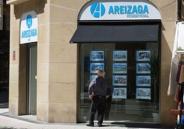Una mujer mira un escaparate de una inmobiliaria en Donostia.