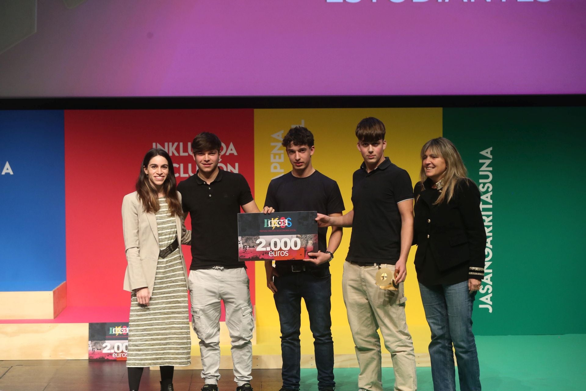 Julen Esteban, Oihan Soto y Sergio Pescador / Inklusioa. Los vencedores del premio EKOS en la categoría Estudiantes Gráfico recogen el premio de manos de Blanca Boix, del equipo de coordinación de REAS Euskadi, y Esther Irigaray, presidenta de FUNKO.
