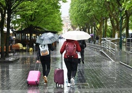Dos turistas caminan con sus maletas por en el Boulevard donostiarra