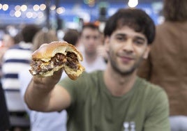 Un asistente a The Champions Burger enseña a cámara una hamburguesa durante la celebración del evento en San Sebastián el pasado mes de julio.