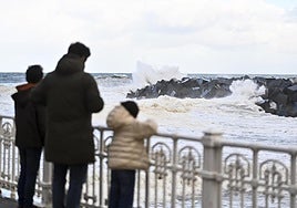 Una familia observa el oleaje en la desembocadura del Urumea