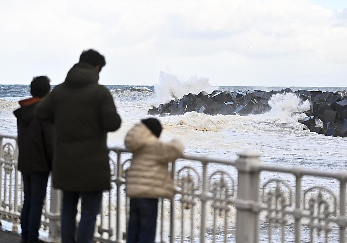 Una familia observa el oleaje en la desembocadura del Urumea