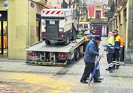 La barredora averiada es remolcada por una grúa.